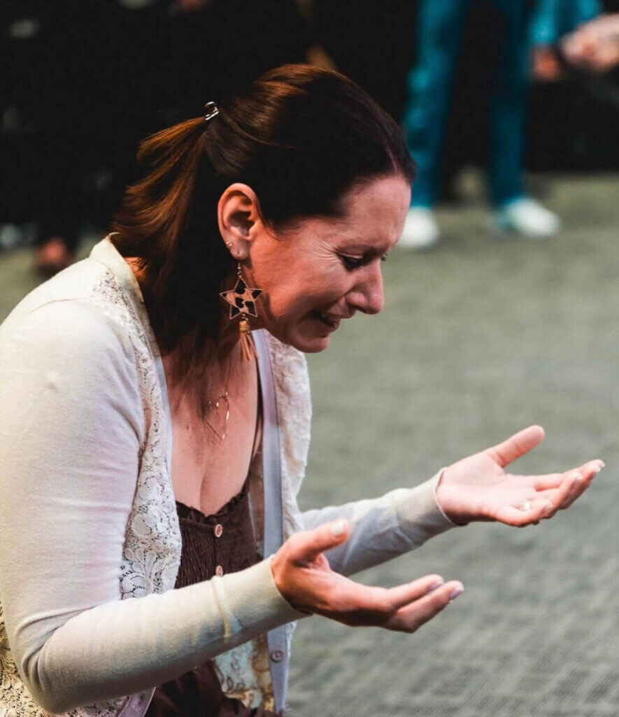 Woman kneeling at a church altar in worship, reflecting surrender and healing from performance-based faith through presence with God